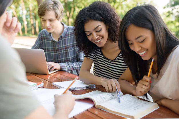 happy-students-sitting-studying-outdoors-while-talking_171337-13401